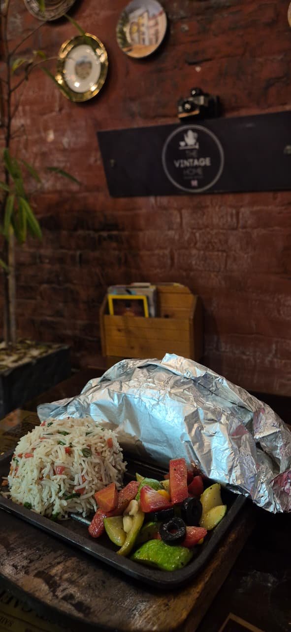 A foil-wrapped platter of grilled chicken and rice, carried out of the Salt Kitchen