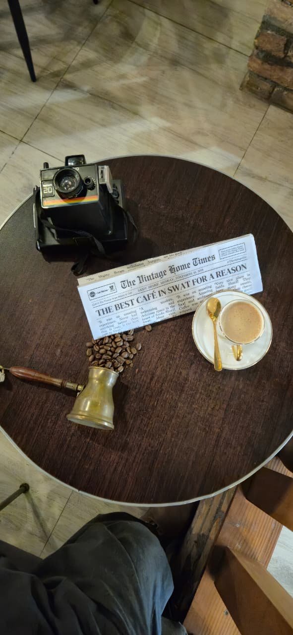 A corner table at The Bar with a coffee, an old camera and The Vintage Home Times